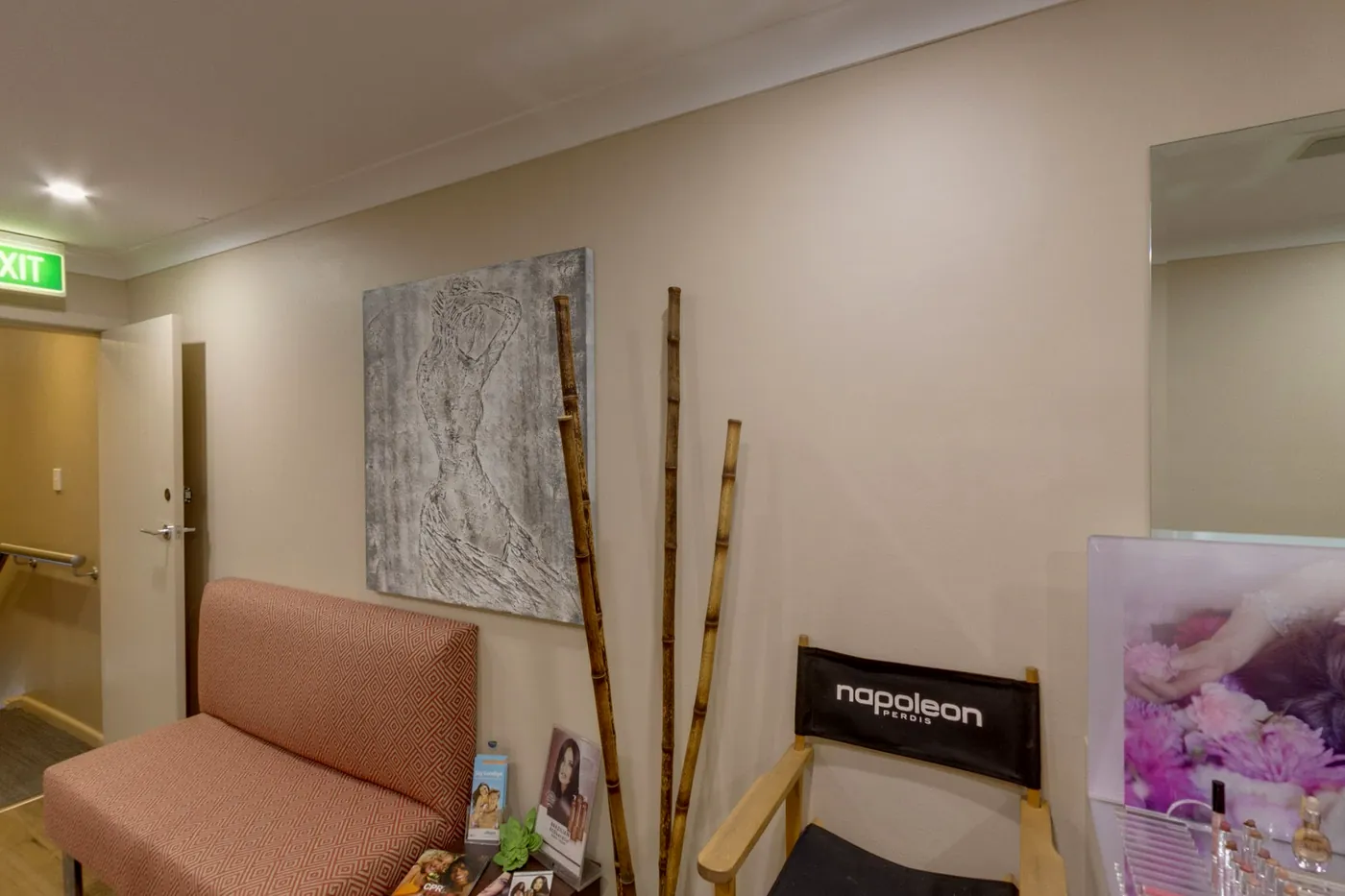Blush pink lounge chair, bamboo stems and textured art in the waiting area